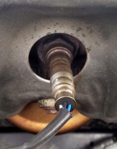 This image shows an oxygen sensor mounted in the exhaust manifold of a vehicle
