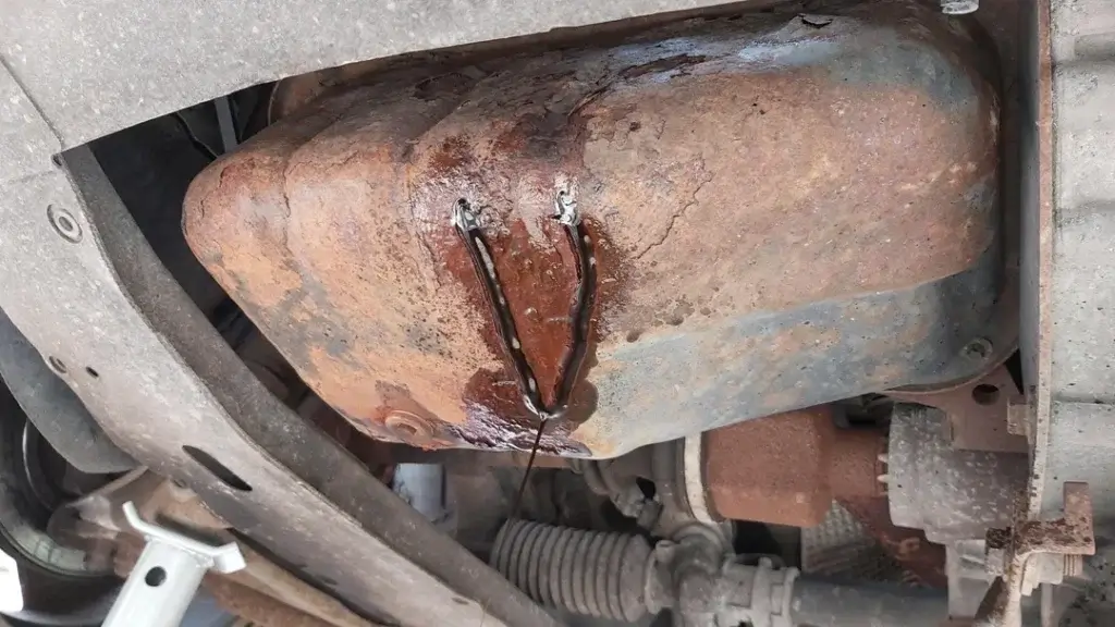 This image shows a rusted oil pan that's leaking oil